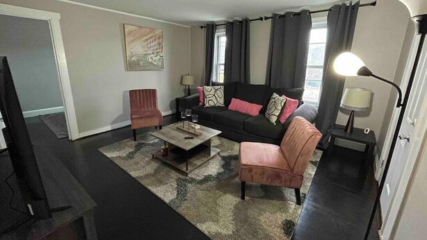 Ein Wohnzimmer mit einer Couch, Sesseln, einem Couchtisch und einem Fernseher.