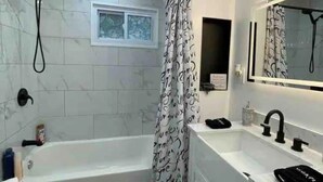 Ein modernes Badezimmer mit einer Badewanne, einem Doppelwaschbecken, einer Toilette und einer Duschkabine.
