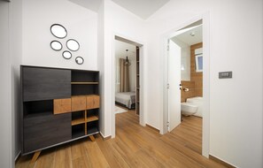 Een moderne slaapkamer met een inbouwkast, een bed en een badkamer zichtbaar door een open deur.