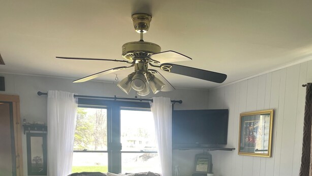 Ein Schlafzimmer mit Bett, Nachttisch und Deckenventilator.