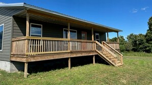 Une maison à deux étages dotée d’une terrasse en bois et d’un escalier menant au deuxième étage.