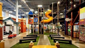 An indoor play area with a large slide, play structures, and a red convertible car. - Birkdale Pool-View, Elevator,Shop-Eat-Work-Play (Huntersville)