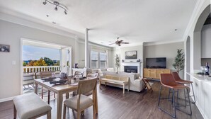 A spacious living area with a dining table, sofas, and a kitchen area. - Birkdale Pool-View, Elevator,Shop-Eat-Work-Play (Huntersville)