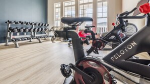 A gym with exercise equipment, including a Peloton bike, dumbbells, and a stationary bike. - Birkdale Pool-View, Elevator,Shop-Eat-Work-Play (Huntersville)