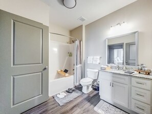 Een moderne badkamer met een bad, toilet en wastafel.