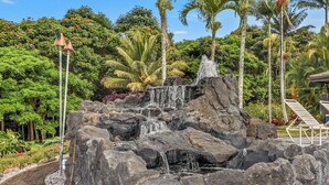 Una cascada rodeada de rocas y palmeras.