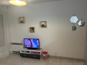 Relax in this stylish living room with a flat-screen TV, decorative shelves, and a cozy seating area.