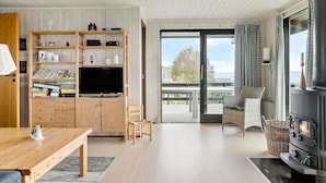 Un salon chaleureux avec un meuble TV en bois, une cheminée et un balcon offrant une vue agréable.