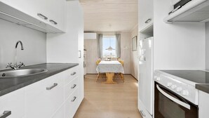 Une cuisine étroite avec un évier, une cuisinière et un coin repas situés au centre.