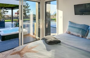 Une chambre à coucher avec un lit, une vue sur la piscine et une porte vitrée donnant sur l’extérieur.