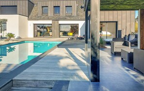 Une maison moderne dotée d’une piscine, de mobilier d’extérieur et d’une terrasse en bois.