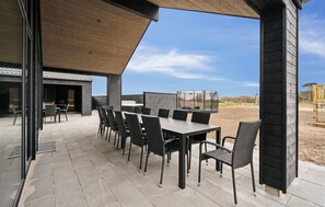 Un patio al aire libre con una zona de estar cubierta, una mesa y sillas.