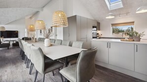 Een moderne keuken met een groot eiland, hangende lampen en een dakraam.