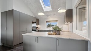 Een moderne keuken met grijze kastjes, een centraal eiland en een dakraam.