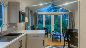 Una cocina moderna con un ventanal grande, un comedor con mesa y sillas, y vistas al exterior.