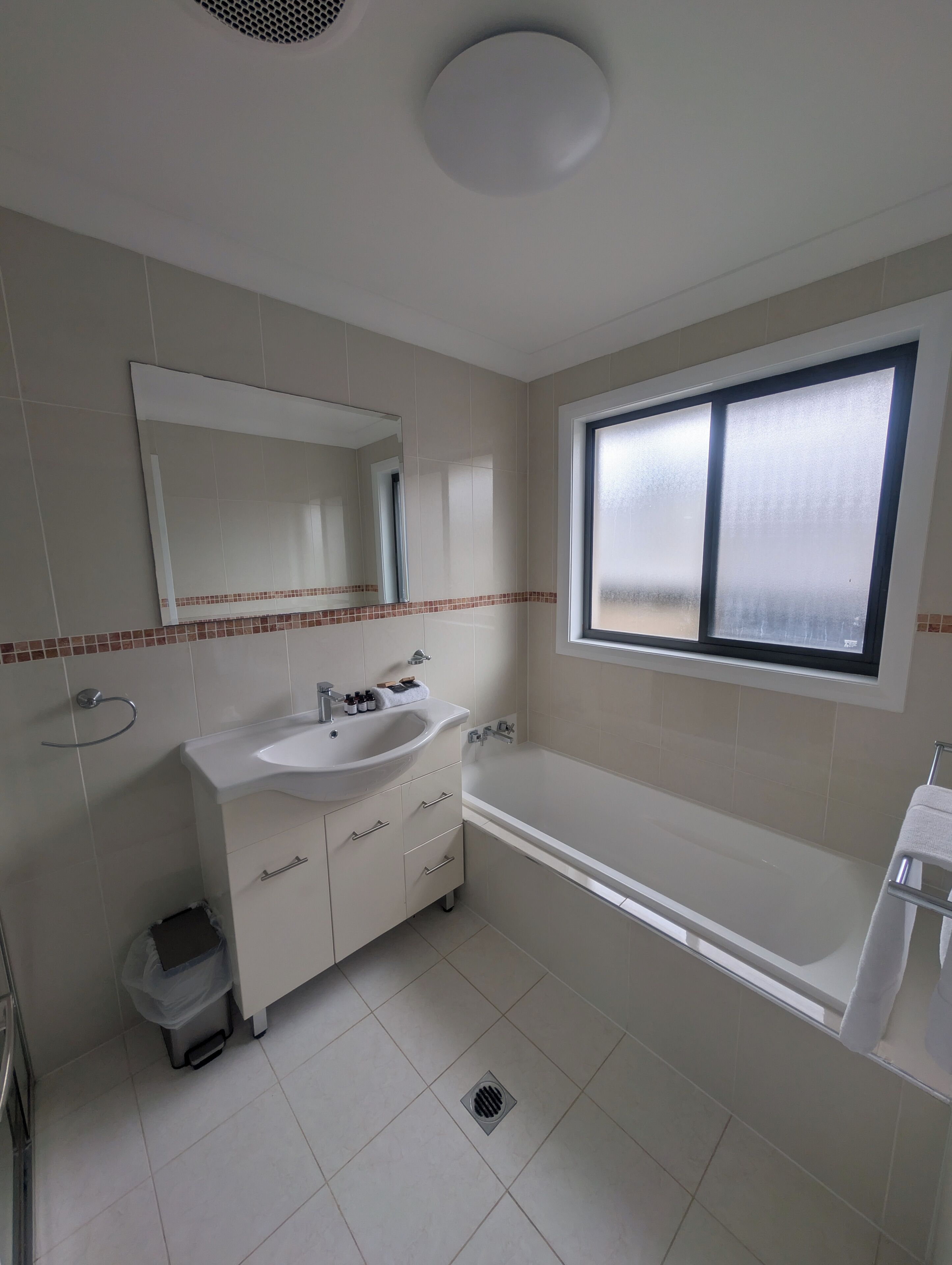 Un baño moderno con un lavamanos grande, espejo y bañera.