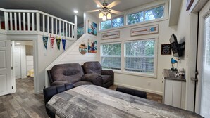 A cozy living room with a sofa, a dining table, and a staircase leading to an upper level.