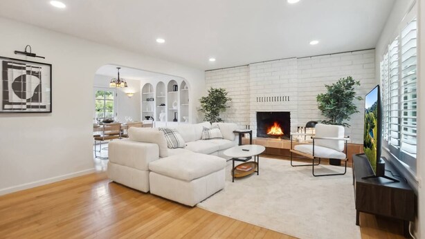 Una sala de estar moderna con un sofá blanco, una chimenea y un televisor.