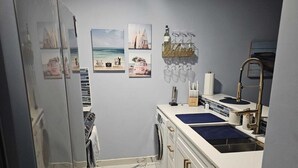 Eine kleine Küche mit Spüle, Arbeitsplatte und einem an der Wand befestigten Weinkühler.