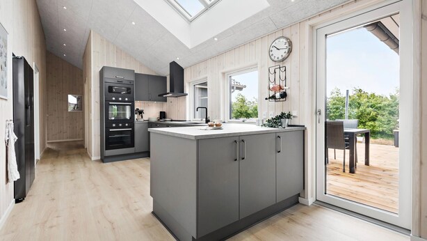 Una cocina moderna con una isla central, horno empotrado y comedor con vistas.