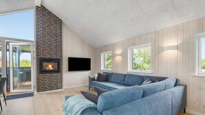 Una sala de estar moderna con chimenea, un sofá grande de color gris y un televisor de pantalla plana.