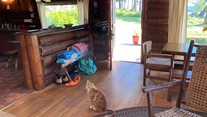 Interior acogedor de una cabaña con un banco de madera, un gato y una zona de comedor.
