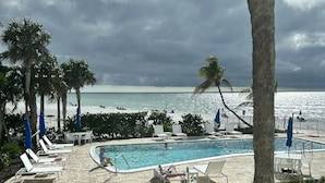 Un espace piscine avec des chaises longues et vue sur l’océan.