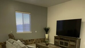 Una sala de estar con sofá, mesa de centro, televisor y plantas decorativas.