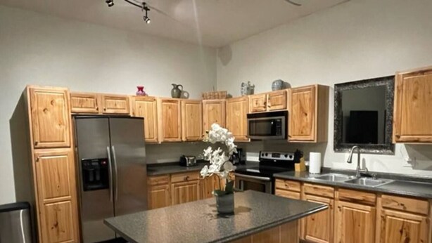 Una cocina moderna con armarios de madera, electrodomésticos de acero inoxidable y una isla central con taburetes.