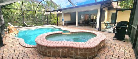 Piscina ao ar livre coberta com hidromassagem, rodeada por um terraço de tijolos e um compartimento de vidro.