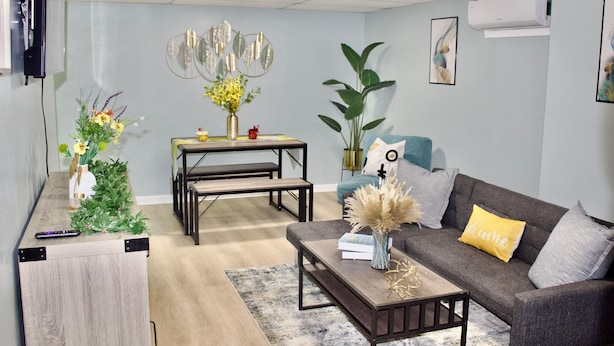 A modern living room with a sofa, coffee table, and a dining area with a table and benches.