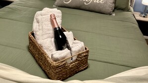 A bed with a bottle of champagne in a basket, a pillow with the word "Grateful," and decorative wall art.