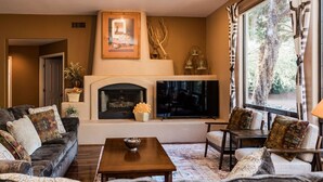A living room with a fireplace, a sofa, a coffee table, and a television.