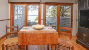 A dining table with four chairs, a bowl, and a view of a backyard with a table and chairs.
