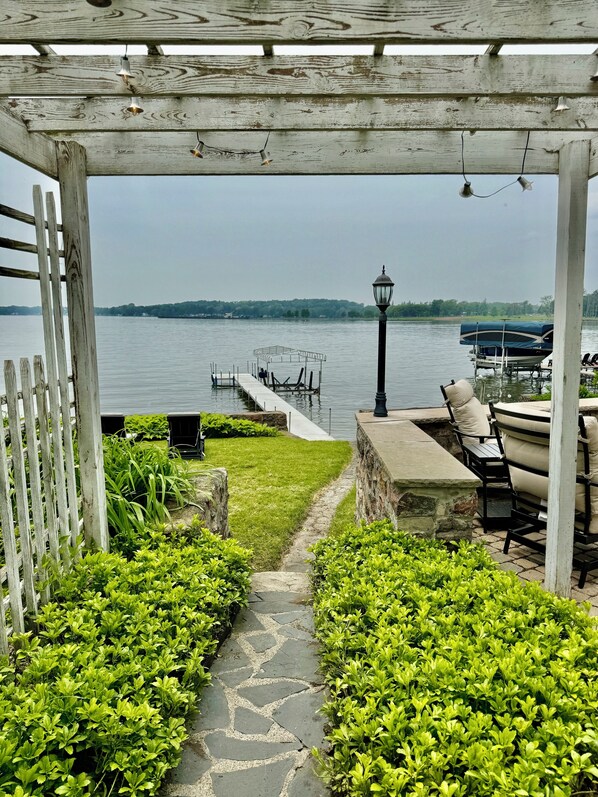 A gazebo with a view of a lake, a pathway, and outdoor seating.