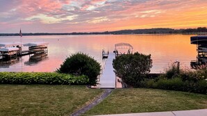 A lakeside view with a dock, boats, and a covered seating area.