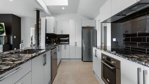 Una cocina moderna con armarios blancos, encimeras de granito y electrodomésticos de acero inoxidable.
