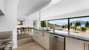 Una cocina moderna con un amplio ventanal, un comedor con mesa y sillas, y vistas a montañas.