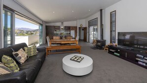 Un salon moderne comprenant un canapé, une table basse, un téléviseur et un coin repas avec un banc et une table.