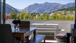 Un balcon avec vue sur les montagnes, une table et des chaises.