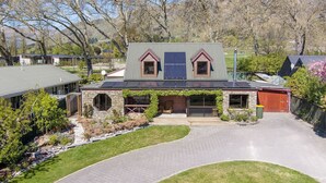 Une maison avec une façade en pierre, un garage et un toit équipé de panneaux solaires.