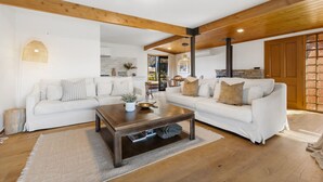 Un salon spacieux avec deux canapés blancs, une table basse en bois et une grande fenêtre.