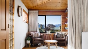 Un salon chaleureux avec deux canapés en cuir, une table basse ronde et une vue sur les montagnes par une grande fenêtre.