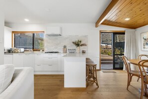 Una cocina moderna con armarios blancos, una isla central y un comedor con sillas de madera.