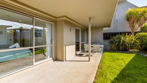 Une maison moderne dotée d’un patio couvert, d’une piscine et d’une pelouse bien entretenue.