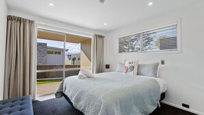 Une chambre avec un grand lit, une vue sur un bâtiment à l’extérieur et une fenêtre avec des stores.