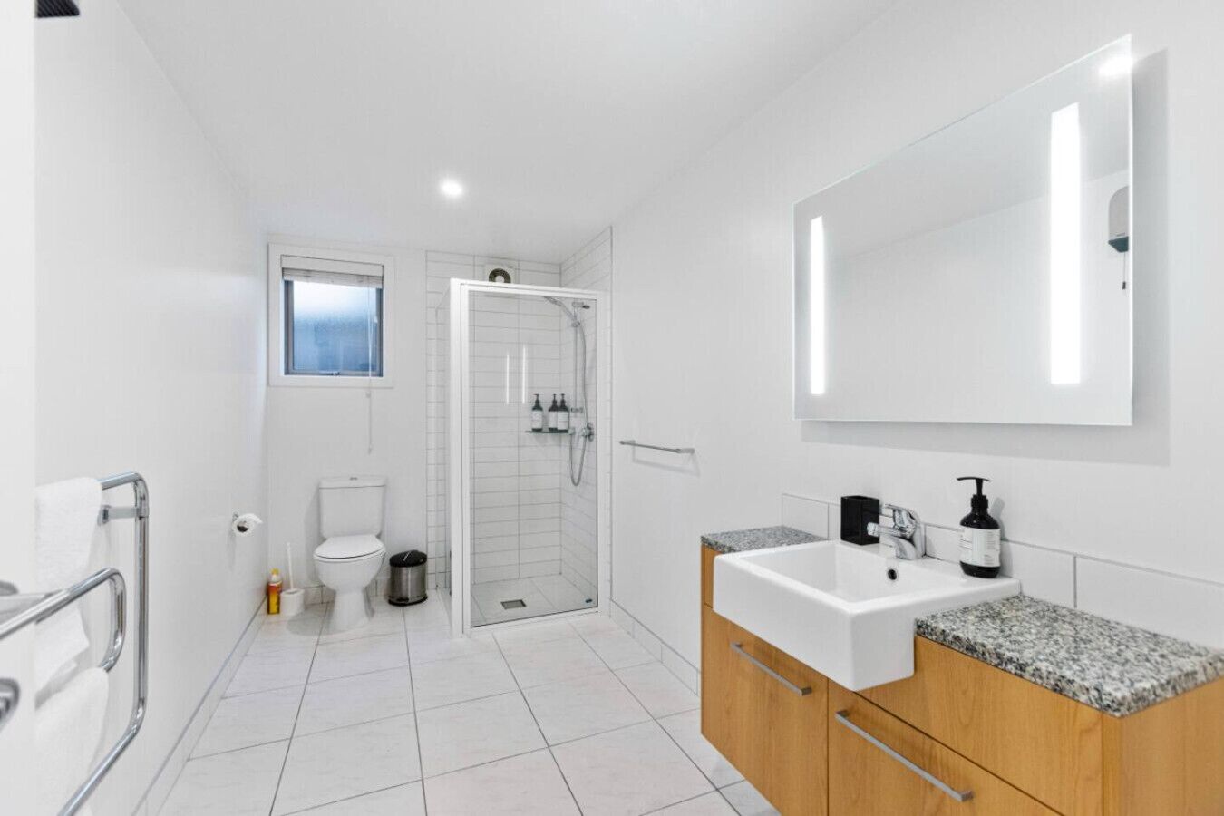 A modern bathroom with a toilet, shower, and sink.