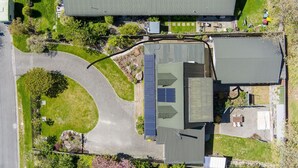 An aerial view of a residential area with a curved driveway, solar panels on a house, and a small garden. - Wanaka Deluxe Studio (Wānaka)