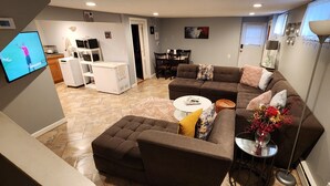 Una sala de estar moderna con un sofá modular, una mesita redonda y un televisor de pantalla plana.