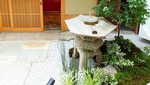 A traditional Japanese garden with a stone lantern, a small tree, and a wooden sliding door. - Sanjoubou Sansou villa (Kyoto)